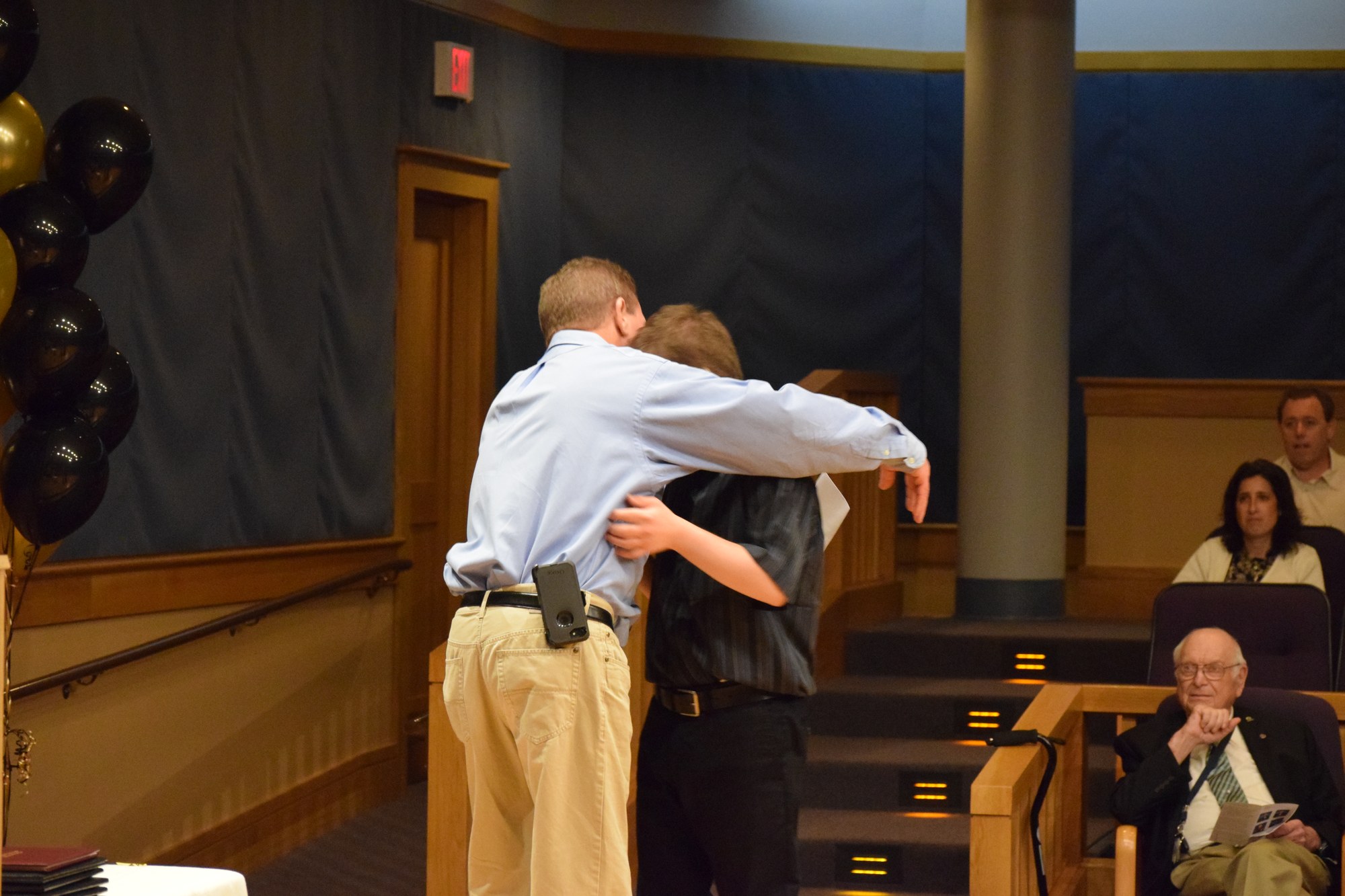 A Mill Neck graduation moment — two students embrace at commencement